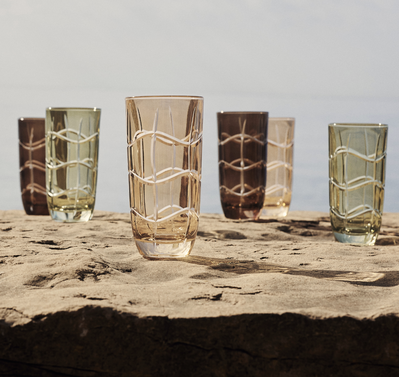 Dior coloured cut-glass tumblers on a rock by the sea